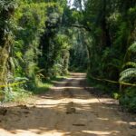 Estrada rural em União Bandeirantes com fita policial isolando área de descoberta