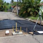 Rua em Porto Cristo com obras de pavimentação e drenagem para mapeamento de infraestrutura.