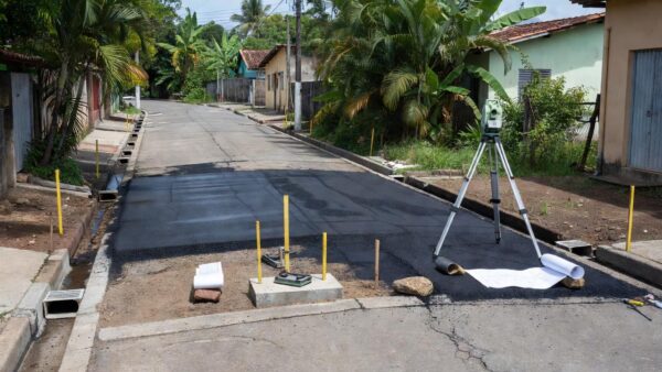 Rua em Porto Cristo com obras de pavimentação e drenagem para mapeamento de infraestrutura.